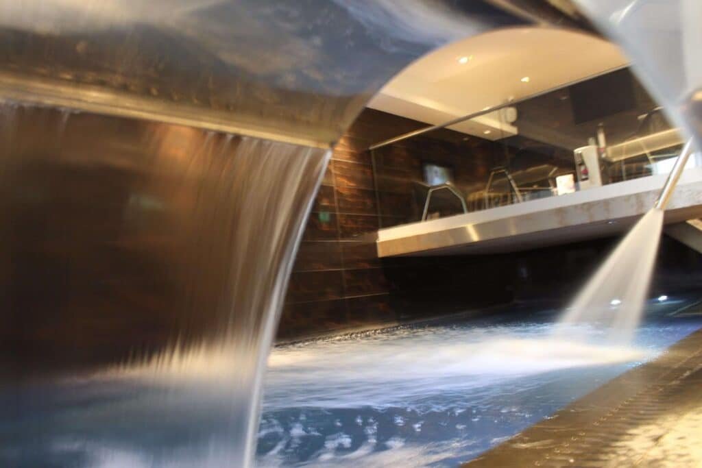 Modern interior swimming pool with shower and fountain.