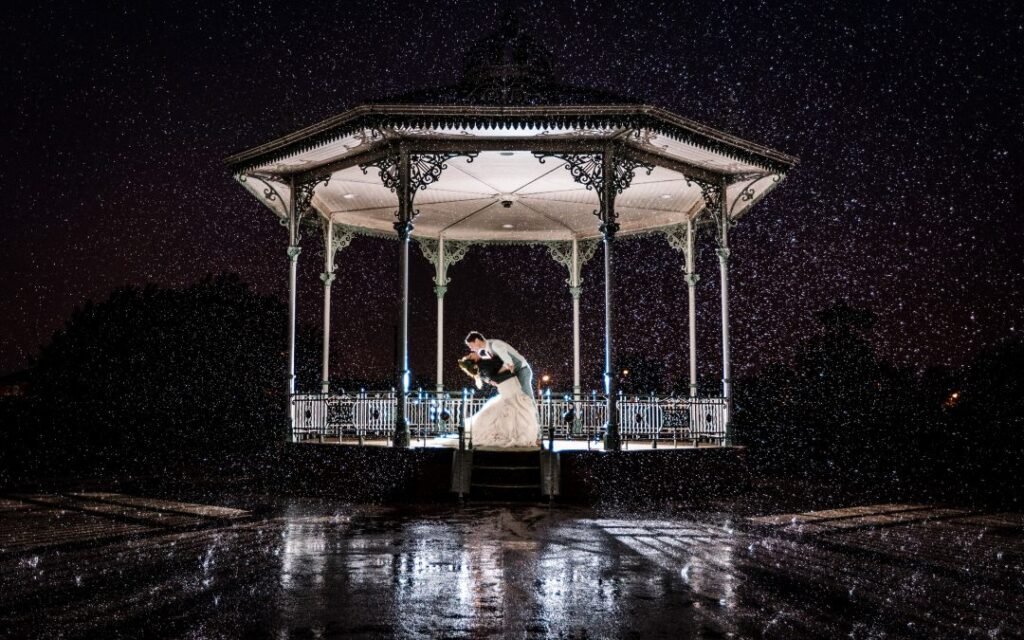 Couple dancing under gazebo together at night.